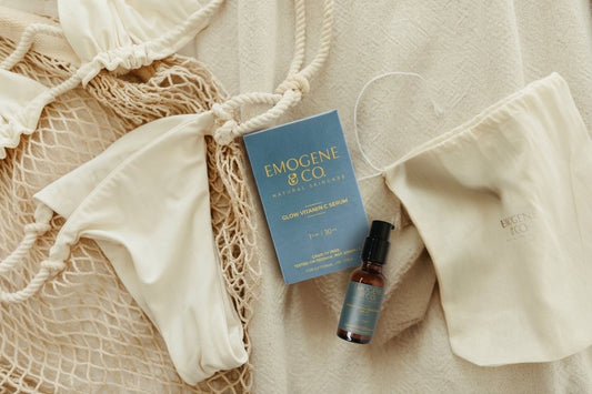Summer Skin Essentials Glow Vitamin C Serum laying next to Radiant Tinted Moisturizer before being packed for a summer vacation next to bathing suit 
