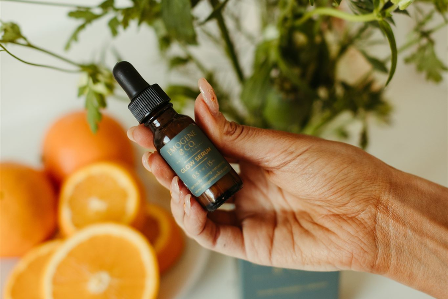 Glow Vitamin C Serum held above oranges to show antioxidants.