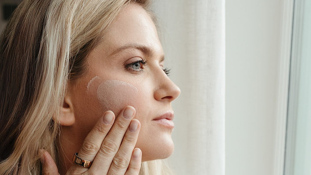 Woman applying skincare to her cheek for healthy glowing skin 